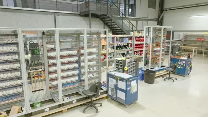 Armoires en cours de câblage sur leurs palettes, chariots d’outillage des câbleurs.